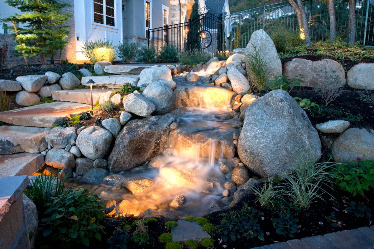 A beautiful landscaped back yard at dusk with landscape lighting.

