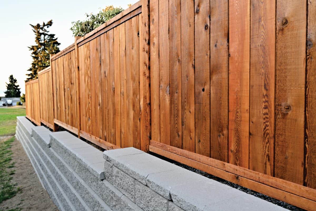 A beautiful view of a staggered retaining block wall of a residential property with a wooden fence behind