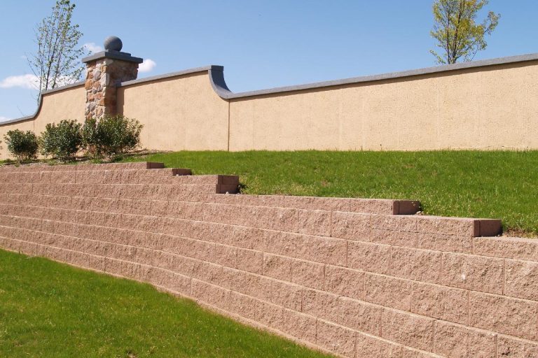 A brick retaining wall by a landscaped yard, Do Retaining Walls Need To Be Waterproofed?