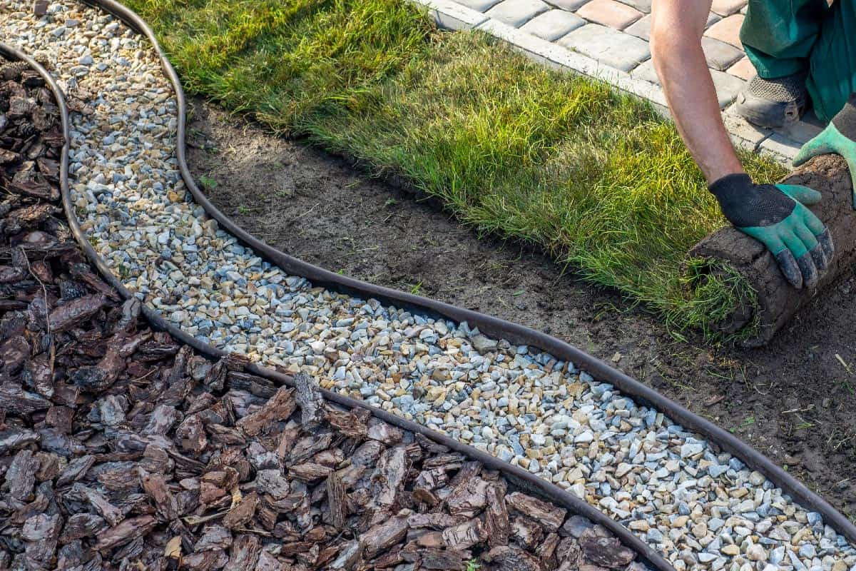 Landscape gardener laying turf near rubber edging border, Can You Cut Rubber Landscape Edging [And How To]?