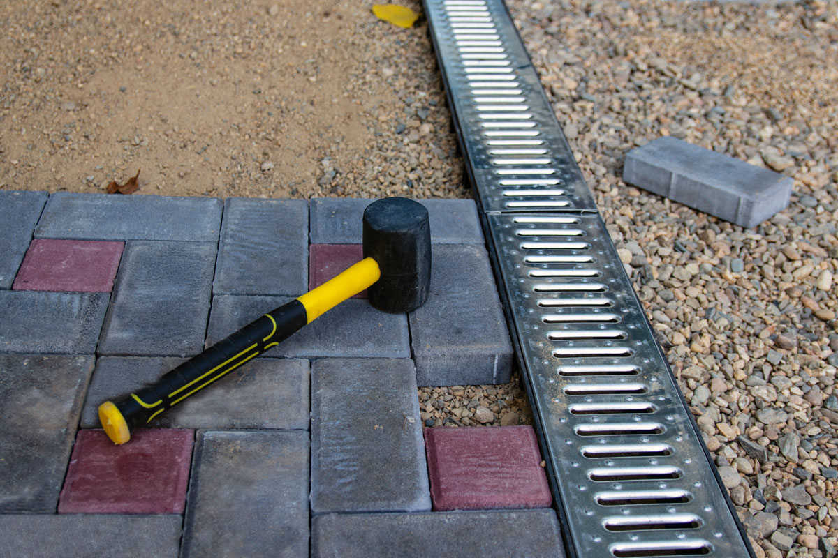 Placing gray and red brick pavers near the patio drain