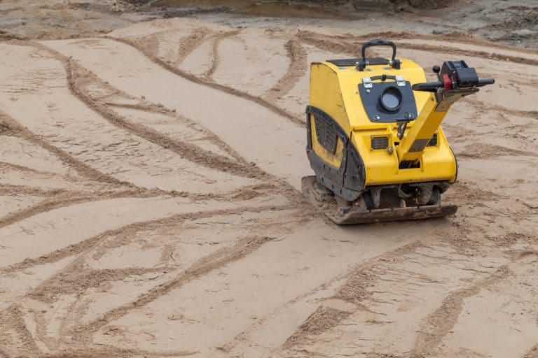 Plate compactor at a construction site - How Much Does Sand Compact