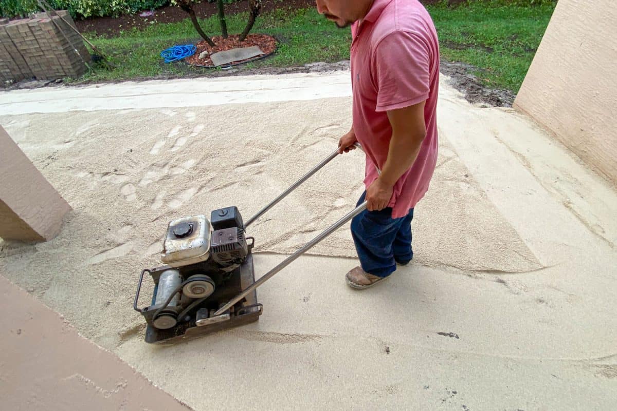 Workman operating a compaction force plate compactor