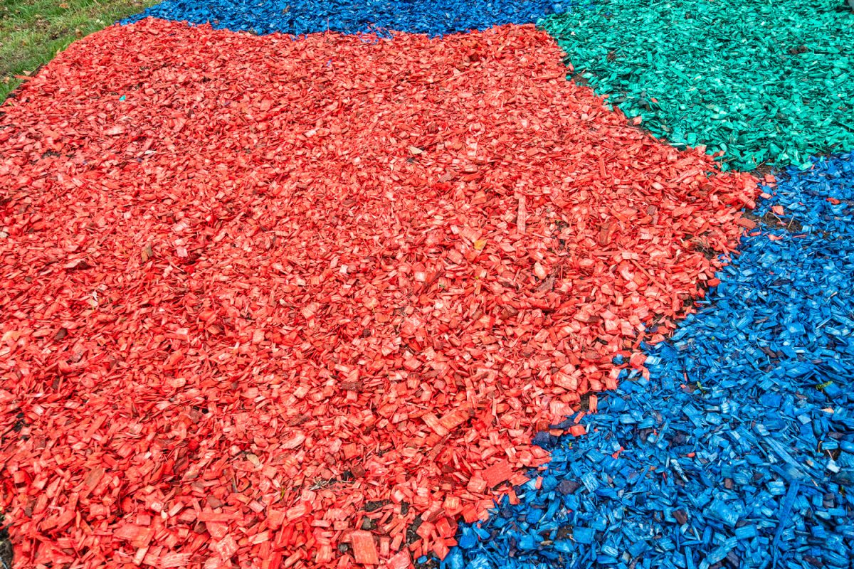 colored layers of wooden mulch on surface of soil on lawn

