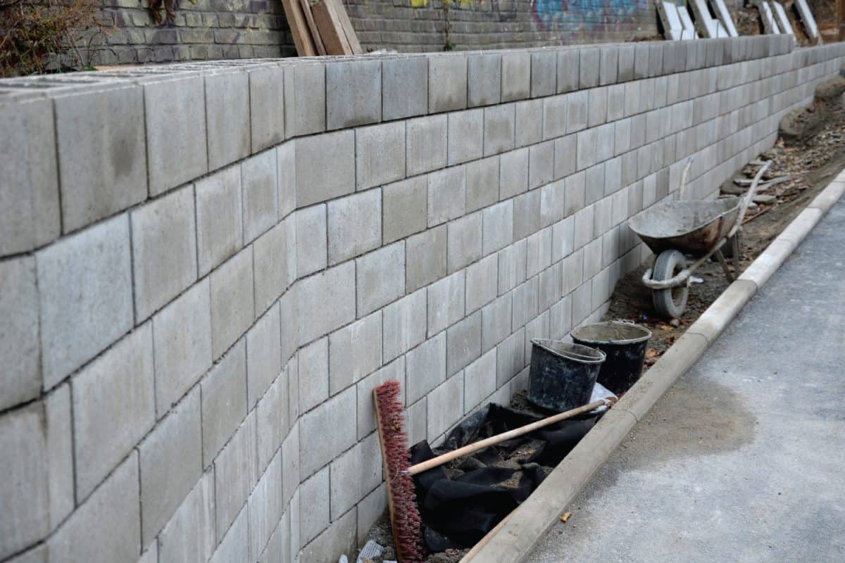 retaining wall with concrete grouting is covered with fake, optically prettier wall.