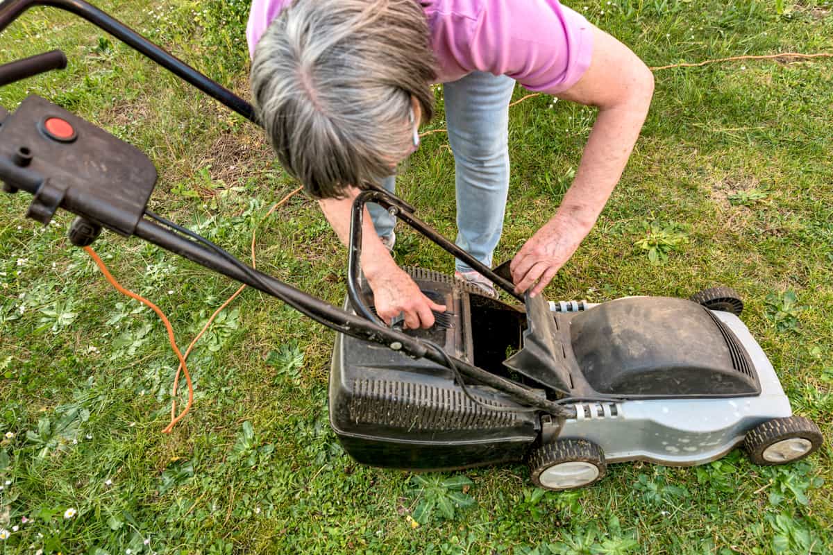 Woman cleaning the lawn mower
