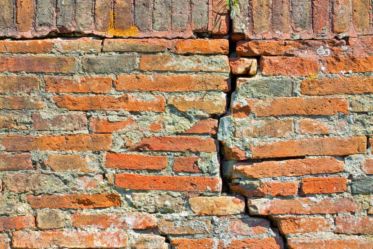 brick wall with a huge crack on it, up close photo of a crack