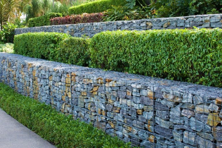stone retaining walls of a green garden, huge rocks, pebbles, How Often Do Retaining Walls Need To Be Replaced?